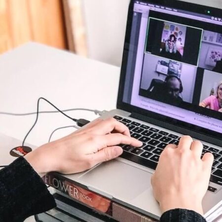 Online class picture with hands on the keyboard and students faces on the screen