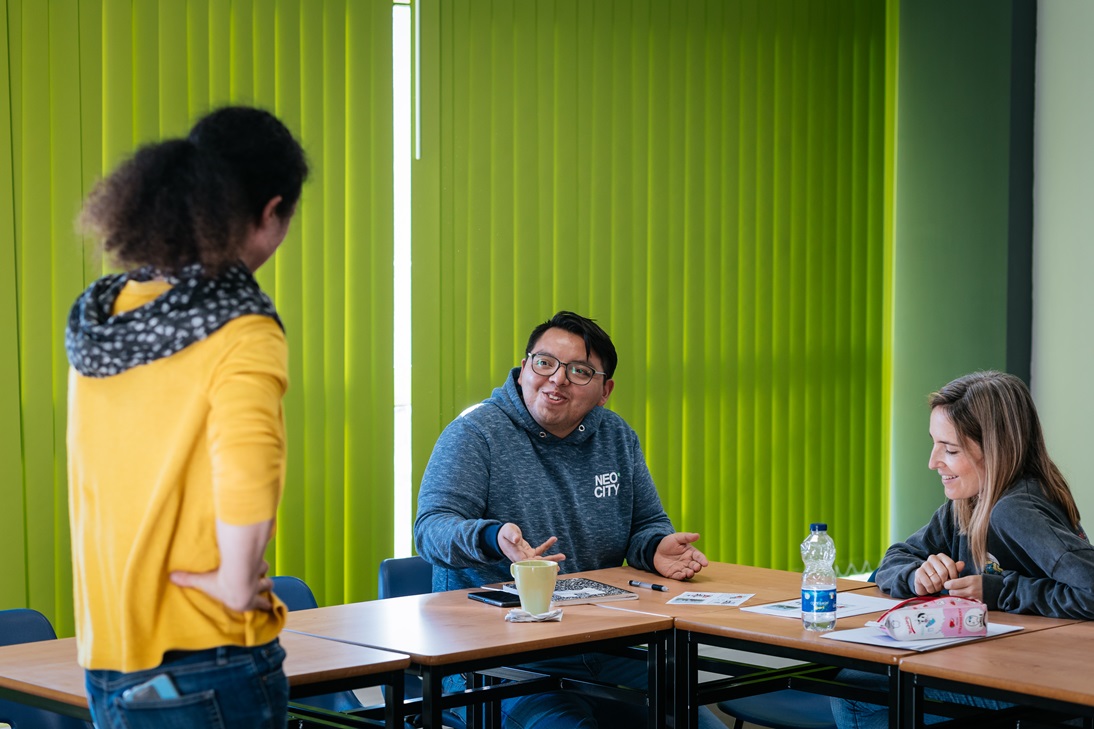 An international student interacts with his teacher and another student in the classroom