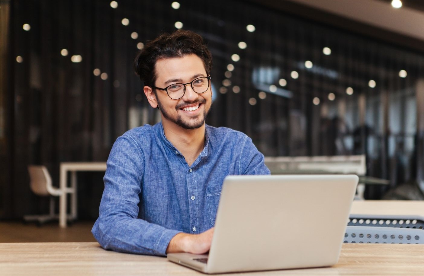 A male at his laptop looking at the camera with a smile